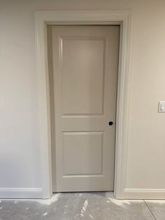 an empty room with a white door and light switch on the right side of the room