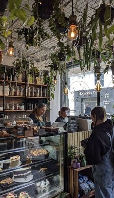 people standing in line at a bakery with cakes and pastries on display behind the counter