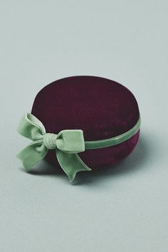 a purple hat with a green bow on the front and side, sitting on a white surface