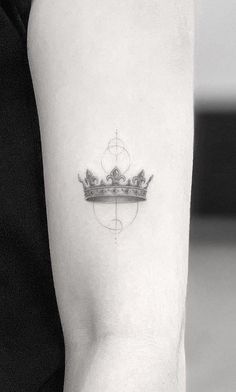 a black and white photo of a crown tattoo on the left arm with an arrow