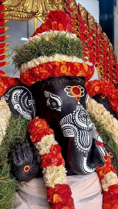 an elephant statue is adorned with flowers and garlands