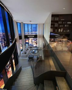 a staircase leading to the top floor of a building with large windows and city lights in the background