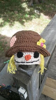 a crocheted scarecrow hat sitting on top of a wooden fence