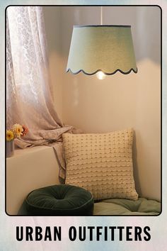 a lamp hanging over a window next to a green pillow on a chair with the words urban outfitters written below it