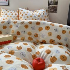 a bed with pumpkins on it and a book sitting on the pillow in front of it