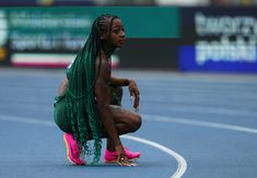 a woman kneeling down on top of a blue track