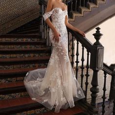 a woman in a wedding dress is standing on the stairs with her hand on her hip