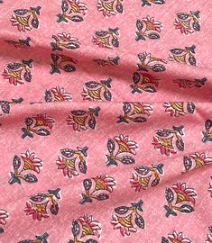 a pink fabric with small flowers and leaves on the side, as well as a red background