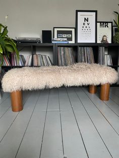 a bench made out of vinyl records in front of a bookshelf filled with cds