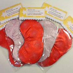 three pieces of red, white and pink mittens in plastic bags with tags on them