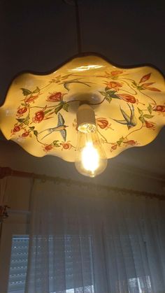 a light that is hanging from the ceiling with flowers on it and birds painted on it