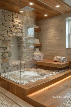 a bathroom with stone walls and wooden flooring, along with a glass enclosed sauna