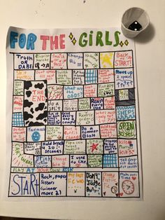 a board game for the girls with words written on it and a cup next to it