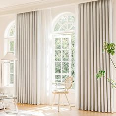 a living room filled with furniture and large windows covered in white curtained drapes