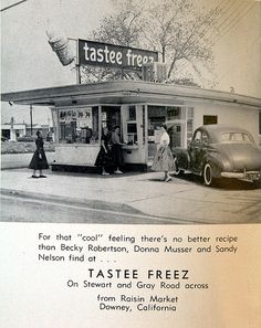 an old advertisement for taste freez on the side of a building with people walking by