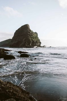 an ocean view with rocks in the foreground and a rock outcropping into the distance