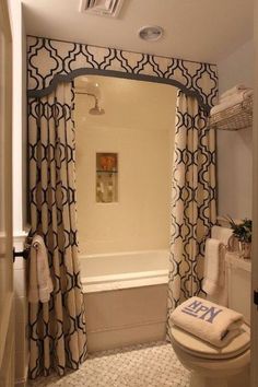 a white toilet sitting next to a bath tub in a bathroom under a light fixture