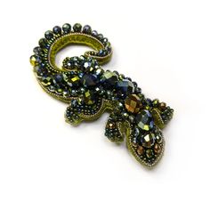 a brooch that is sitting on a white surface and has beads all over it