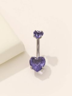 a pair of purple heart shaped earrings sitting on top of a white surface