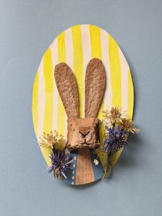 a paper plate with a rabbit head and flowers on it, against a blue background