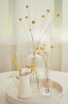 two vases filled with yellow flowers sitting on top of a white table next to each other