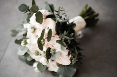 a bridal bouquet with white flowers and greenery on the floor at a wedding