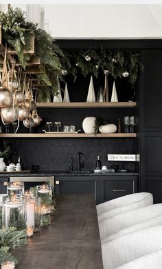 a dining room table with candles and christmas decorations on the shelf above it, surrounded by greenery