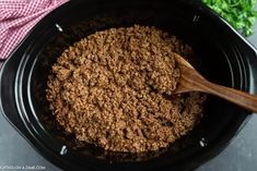 a crock pot filled with ground beef and garnished with a wooden spoon