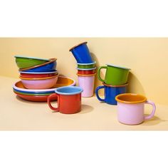 a group of colorful cups and plates stacked on top of each other in front of a yellow wall