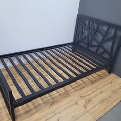 a metal bed frame sitting on top of a hard wood floor next to a wall