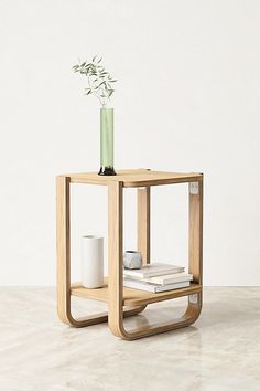 a small wooden table with a vase and some books on the shelf next to it