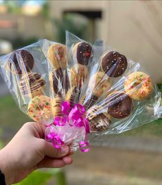 a hand holding a bunch of cookies wrapped in cellophane and sprinkled with pink flowers