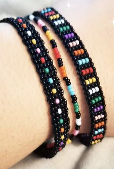 three bracelets with different colored beads are on the arm and one has a star in the background