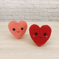 two crocheted hearts sitting next to each other on top of a wooden table