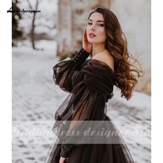 a woman in a black dress posing for the camera with snow on the ground behind her