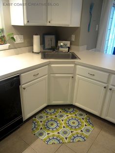 a kitchen with white cabinets and an area rug that looks like it has been cut in half