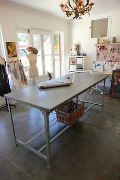 a large table sitting in the middle of a room with clothes on display behind it