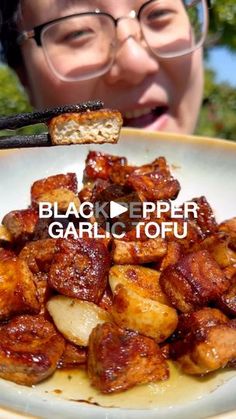 the woman is eating her food with chopsticks in front of her face and text that reads black pepper garlic tofu