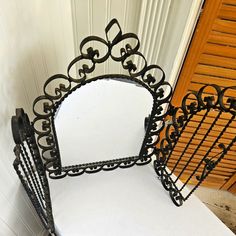 there is a mirror on top of a white table with black iron bars around it