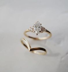 two gold rings with diamonds on them sitting next to each other in front of a white background