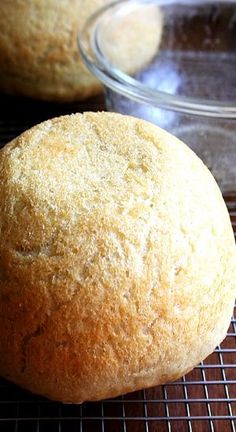 two muffins sitting on top of a cooling rack next to a glass bowl