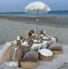 a table set up on the beach with an umbrella