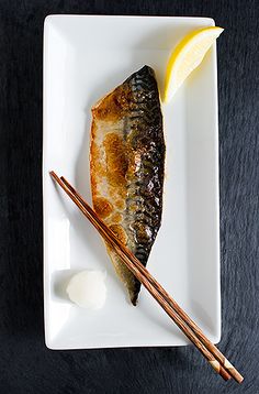 a white plate topped with fish and chopsticks