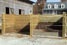 a fenced in area next to a building with a pile of dirt on the ground