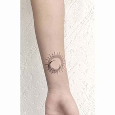 a woman's arm with a small sun tattoo on the left side of her wrist