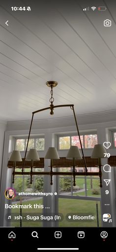 the light fixture is hanging from the ceiling in front of two windows with an open window behind it