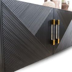 a large black cabinet with gold handles on it's sides and an interesting design