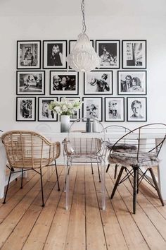 a dining room table with chairs and pictures on the wall behind it in black and white