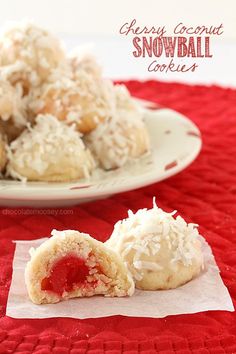 some coconut snowball cookies are on a red tablecloth and one is half eaten