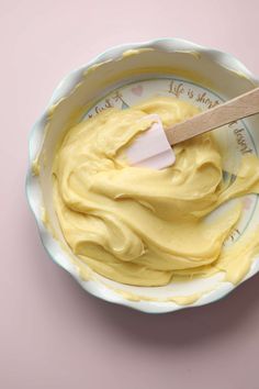 a bowl filled with yellow icing and a wooden spoon